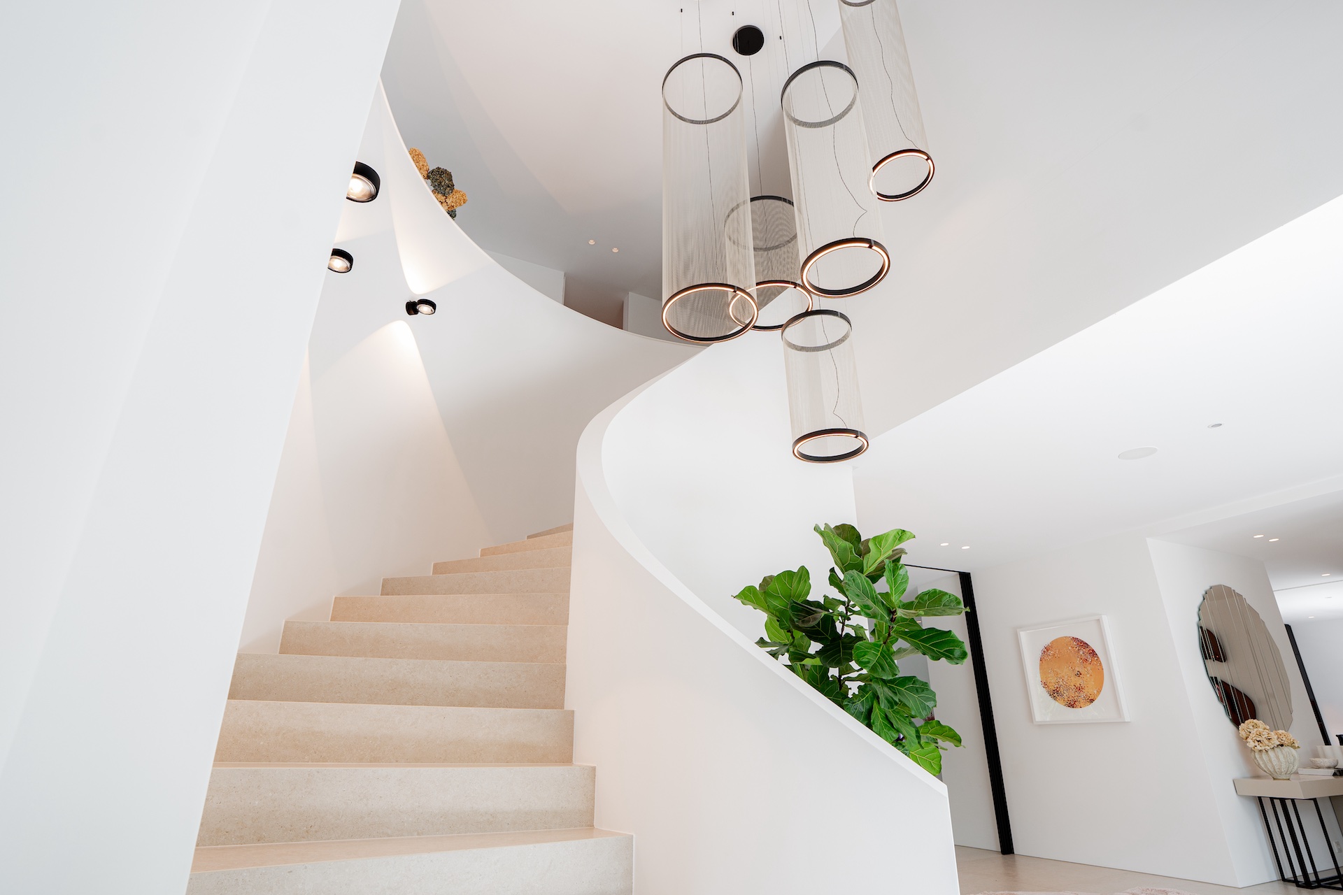 Treutlein Interior Design: geschwungene, freitragende Treppe mit skulpturalem Ring-Pendelleuchter