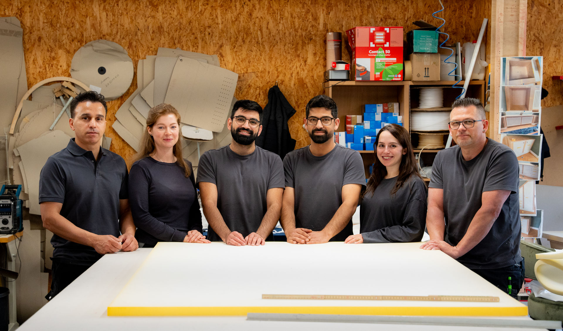 Das Treutlein Team steht gemeinsam in der Manufaktur um einen Arbeitstisch