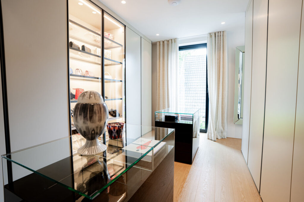 Ankleidezimmer mit beleuchteter Glasvitrine und Glastisch