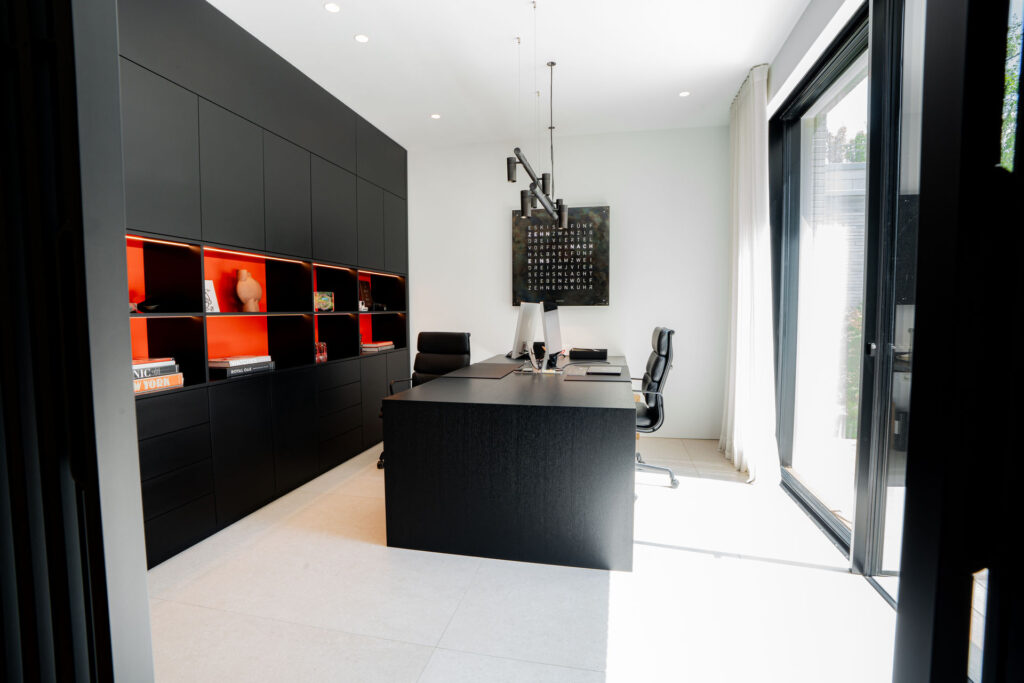 Arbeitszimmer mit schwarzer Einbauwand, Schreibtisch und orangen Akzenten