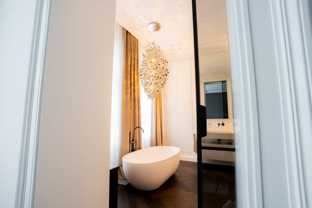 Durchblick auf eine freistehende Badewanne mit Kronleuchter