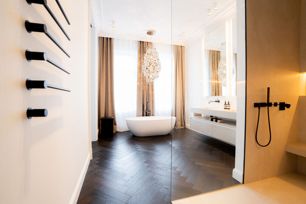 Badezimmer mit freistehender Badewanne, Fischgrätparkett und schwarzen Handtuchhaltern