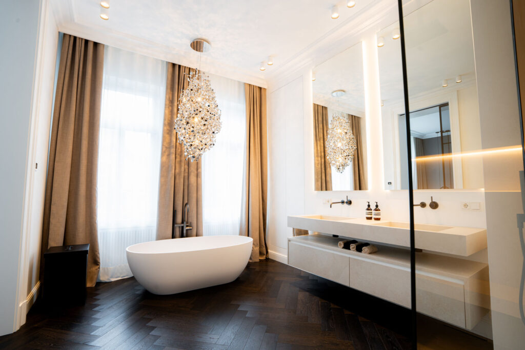 Badezimmer mit freistehender Badewanne, Kronleuchter und Doppelwaschtisch