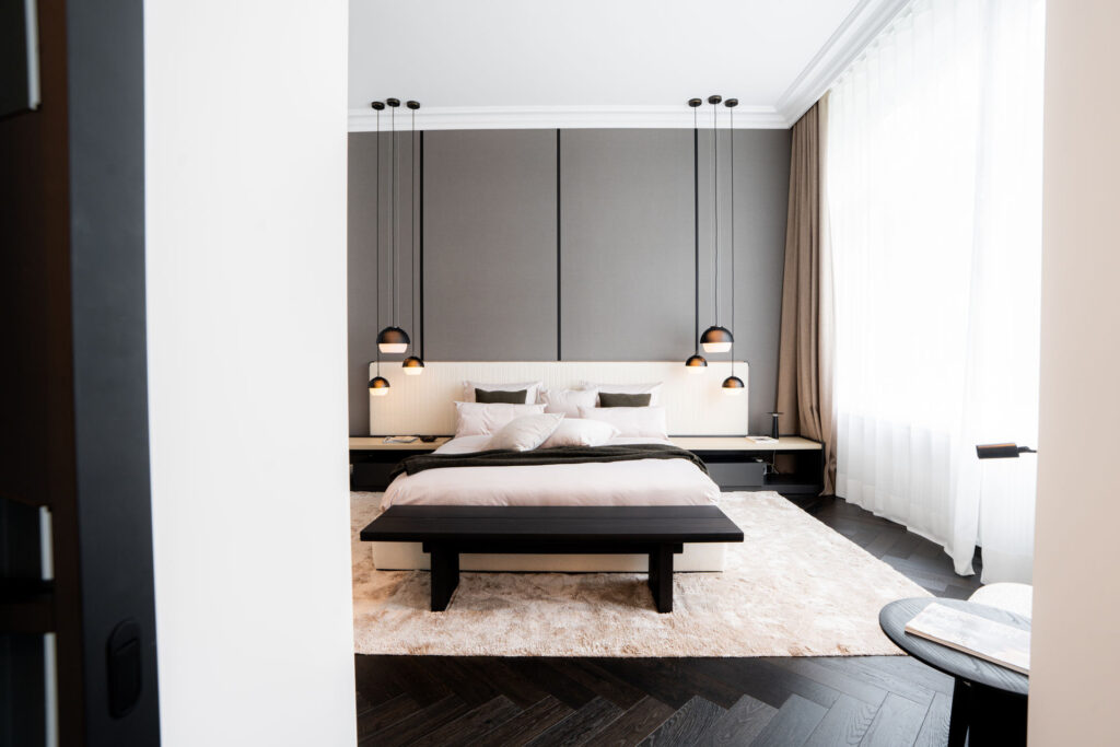 Schlafzimmer mit Paneelwand, Pendelleuchten und dunkler Sitzbank