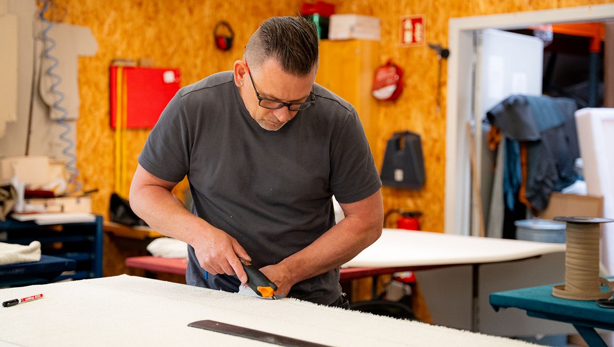 Mitarbeiter der Treutlein Manufaktur schneidet in der Werkstatt Stoff zu