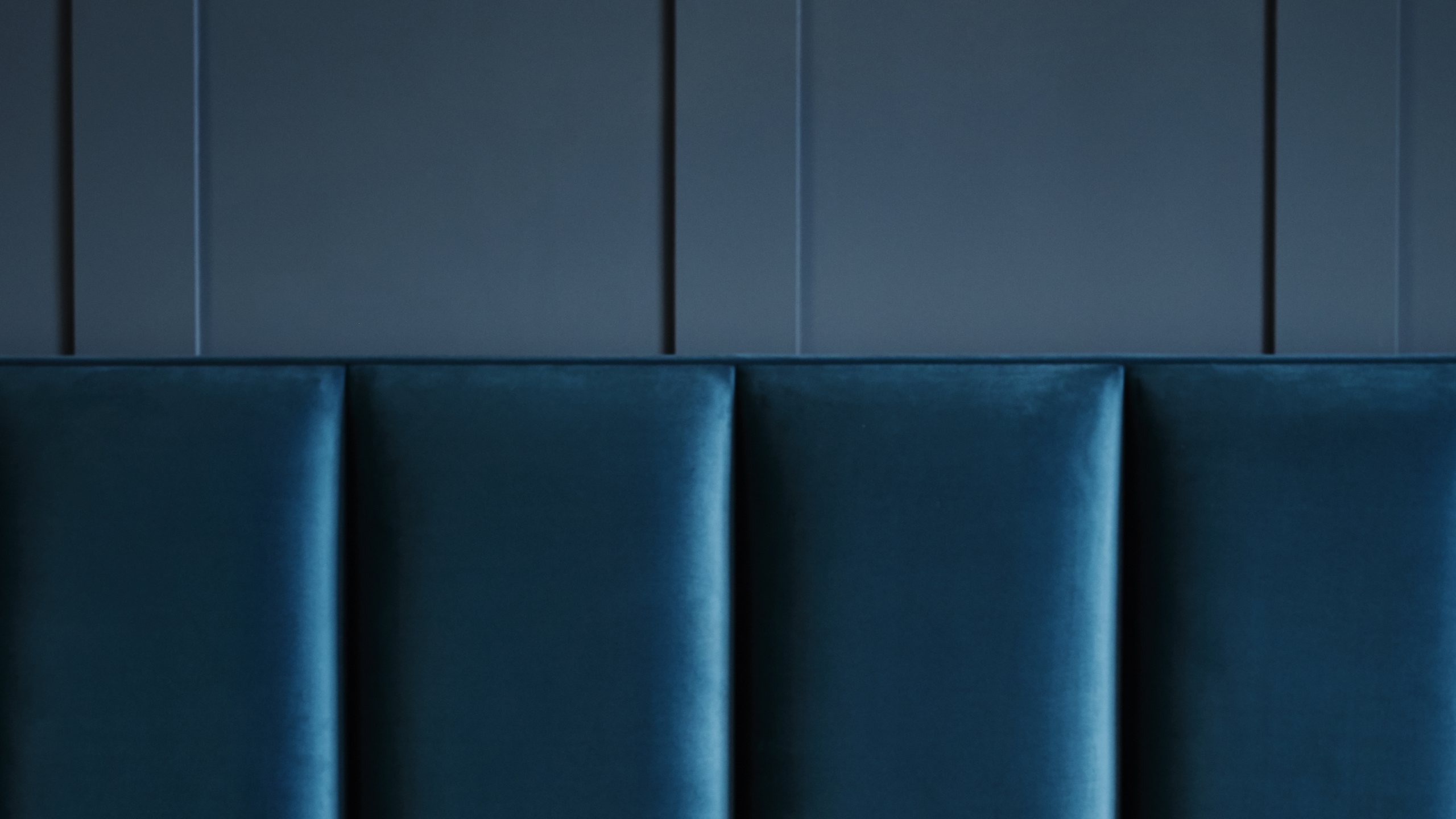 Gepolstertes Vispring Kopfteil aus blauem Samt vor dunkelblauer Wand