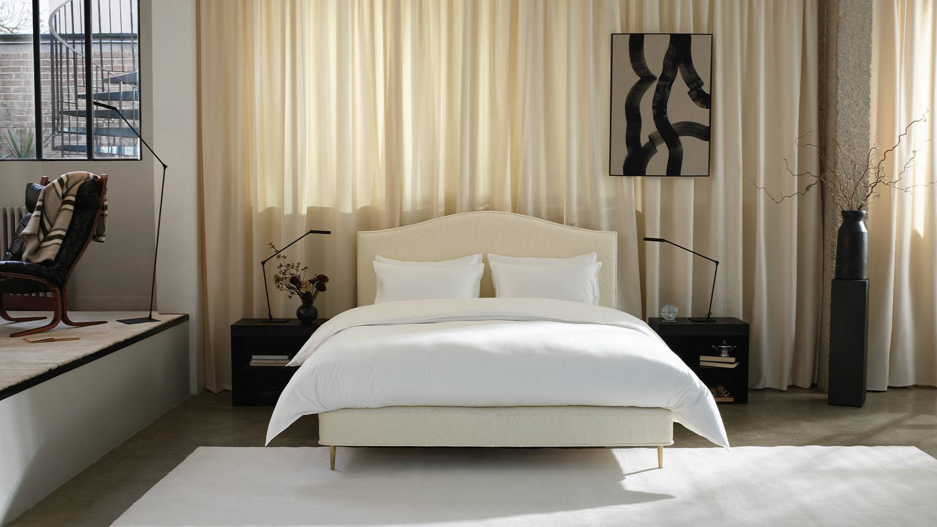 Vispring Bett der Original Kollektion mit cremefarbenem Kopfteil vor hellen Vorhängen